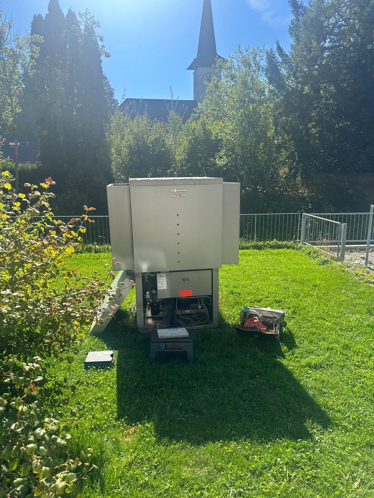 Wärmepumpe im Aussenbereich auf einer Rasenfläche, Gehäuse für Arbeiten geöffnet